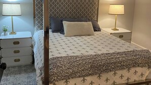 A four-poster canopy bed with a patterned bedspread, two bedside tables with lamps, and a nightstand with drawers. - NOLA Vibe/Oversized 1 bedroom/Entire unit (Kansas City)