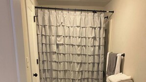A bathroom with a white toilet, a sink, and a shower curtain. - NOLA Vibe/Oversized 1 bedroom/Entire unit (Kansas City)