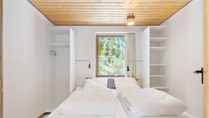 A room with a bed, a window with a view of trees, and built-in shelving. - 5 bedroom amazing home in Herning (Herning)