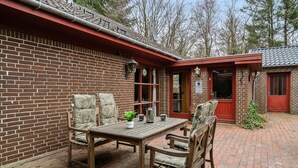 A brick building with a red door and a small garden area with a table and chairs. - 5 bedroom amazing home in Herning (Herning)