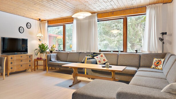 A cozy living room with a sofa, TV, wooden cabinet, and a dining table. - 5 bedroom amazing home in Herning (Herning)