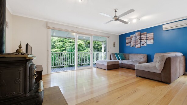 A spacious living room with a large sliding glass door leading to a balcony, a ceiling fan, and a blue accent wall. - Purple Goose at Red Rocks (Cowes)