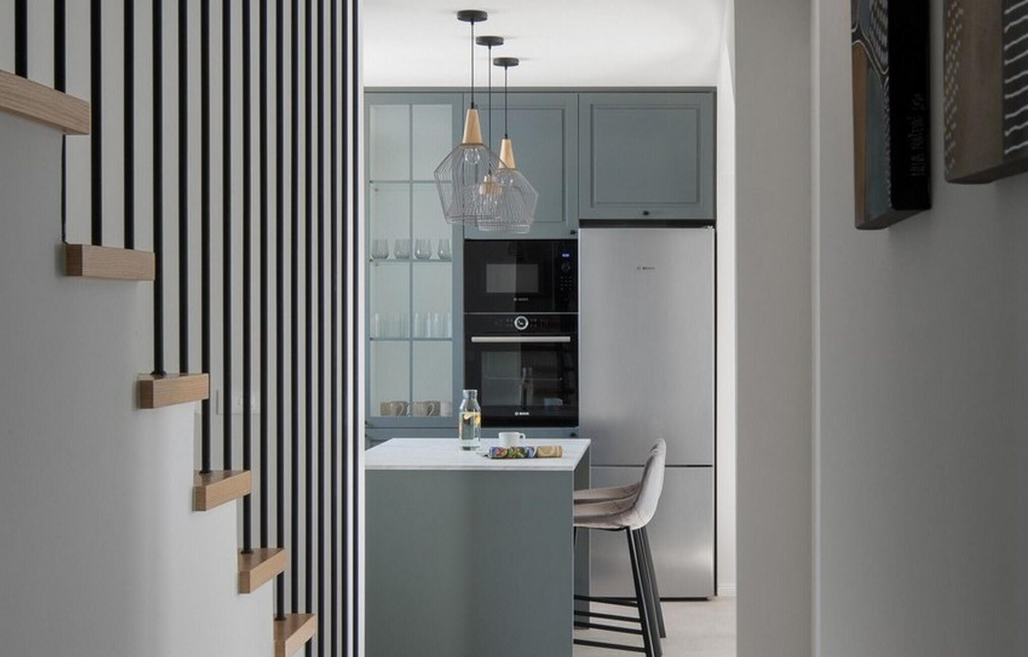 A modern kitchen with a central island, a built-in oven, and a refrigerator.