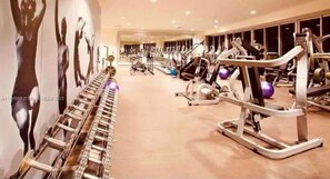 A gym with various exercise machines and a mirrored wall. - Sky Lights Lux Suite (Miami)