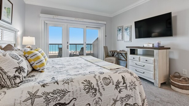 Un dormitorio con cama, televisor, escritorio y vista al océano.