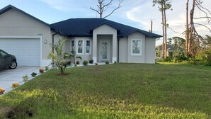 A two-story house with a garage, a driveway, and a well-maintained lawn. -  New Home only minutes away from beautiful sandy beaches (Port Charlotte)