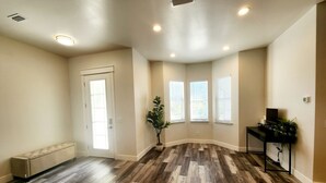 A spacious room with a herringbone wood floor, a bench, a potted plant, and a desk with a computer. -  New Home only minutes away from beautiful sandy beaches (Port Charlotte)