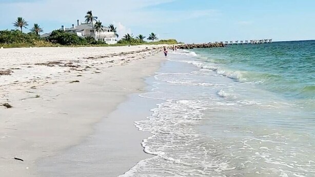 A beach with clear water, a sandy shore, and a few people in the distance. -  New Home only minutes away from beautiful sandy beaches (Port Charlotte)
