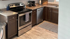A modern kitchen with dark brown cabinets, stainless steel appliances, and a granite countertop.
