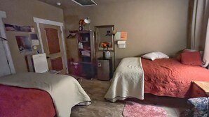 A bedroom with two beds, a dresser, a mirror, and a door.