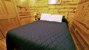 A wooden cabin room with a bed, a nightstand, and a lamp. - 1 Bedroom 1 Bath Cabin with hot tub (Beaver, WV) (Beaver)