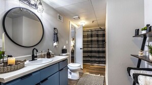 Une salle de bain moderne avec un grand miroir, deux vasques et des toilettes.