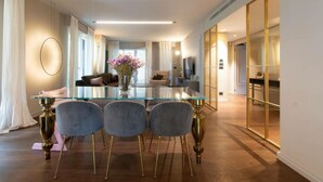 A modern living room with a glass coffee table, four grey chairs, and a vase of flowers. - Beautiful 2-bed Apartment in Torino (Turin)