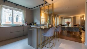 A modern kitchen with a bar area, large windows, and a view of a building with 'ROMA ALE' signage. - Beautiful 2-bed Apartment in Torino (Turin)