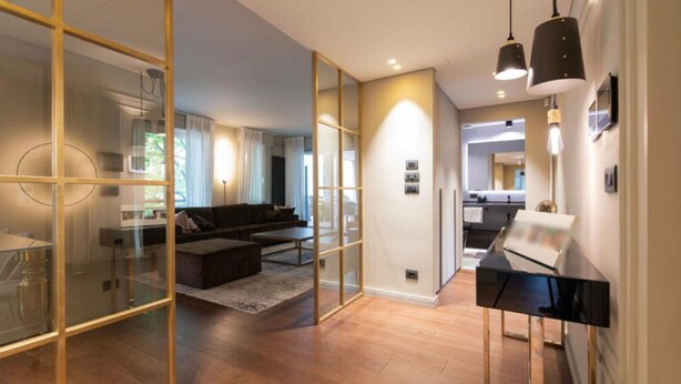 A modern interior with a glass partition, a living area with a sofa and coffee table, and a kitchen area with a countertop and sink. - Beautiful 2-bed Apartment in Torino (Turin)