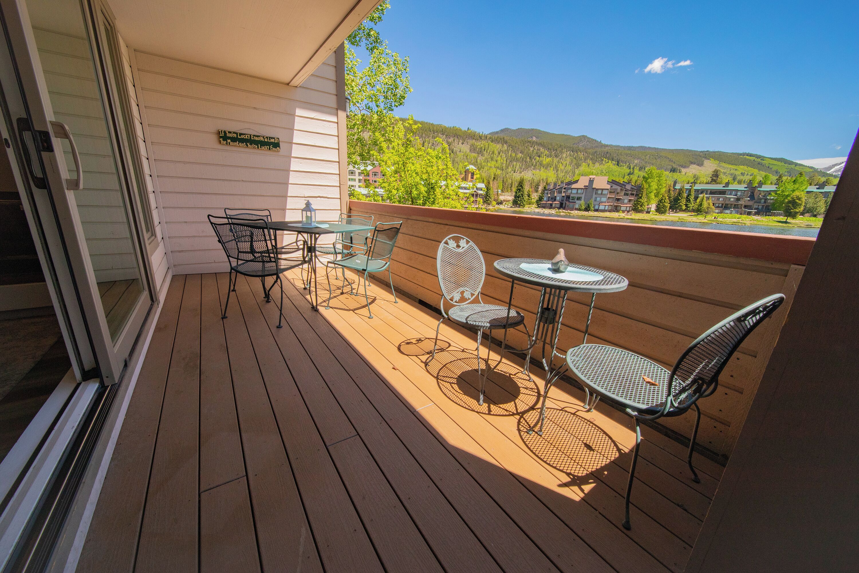 A wooden deck with outdoor furniture, a glass door, and a view of a mountain and buildings.