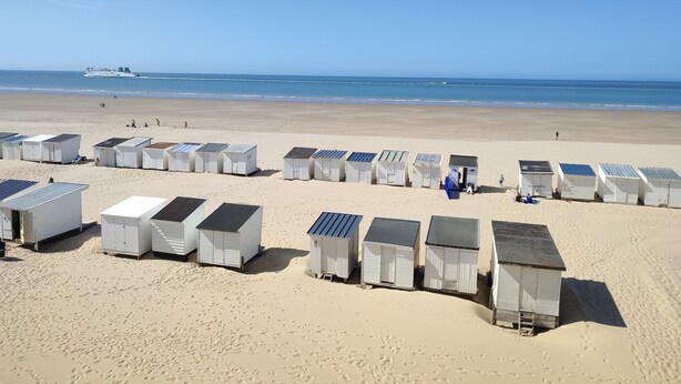 A beach with rows of small, white beach huts with solar panels on the roofs. - Appartement Avec Magnifique vue sur Port Situé Entre la Plage et le Centre Ville (Calais)