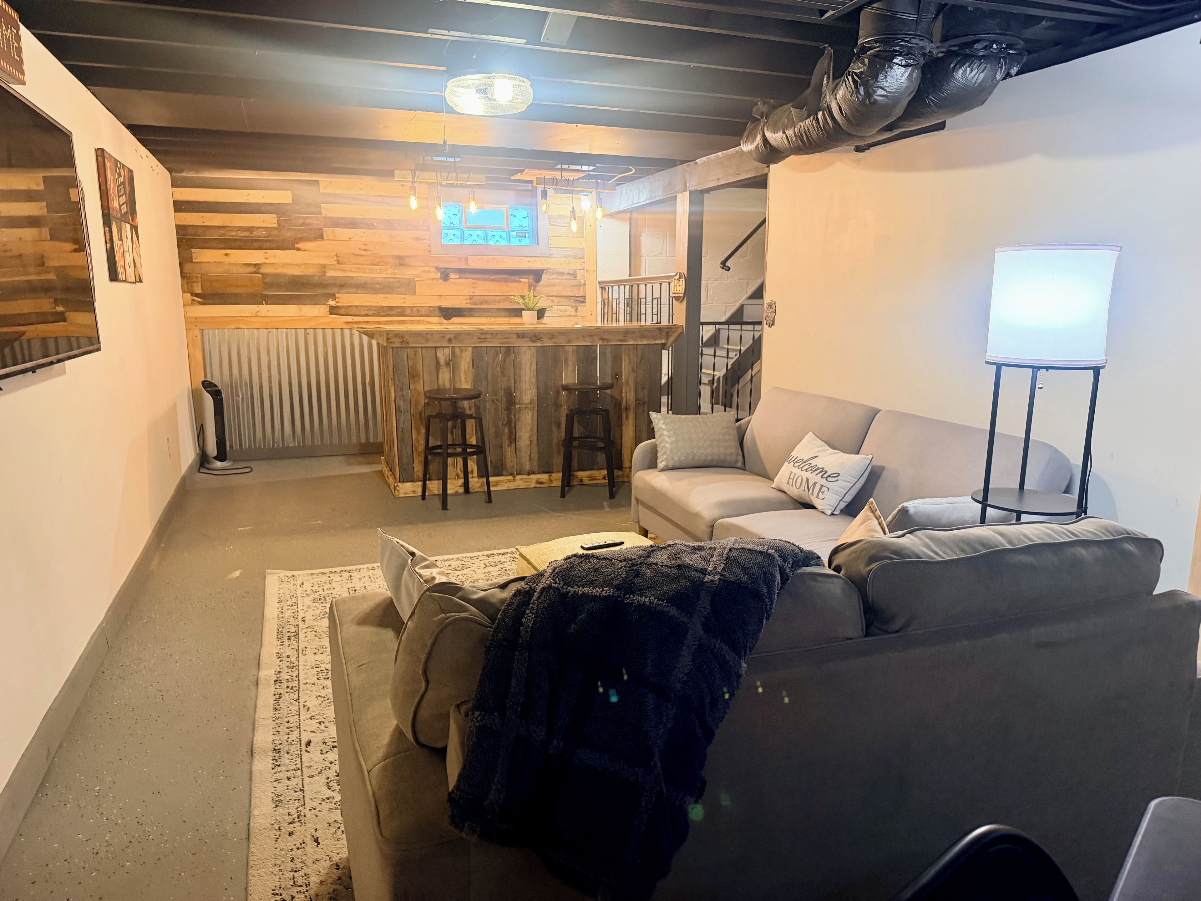 A modern living room with a sofa, a coffee table, and a bar area with stools.