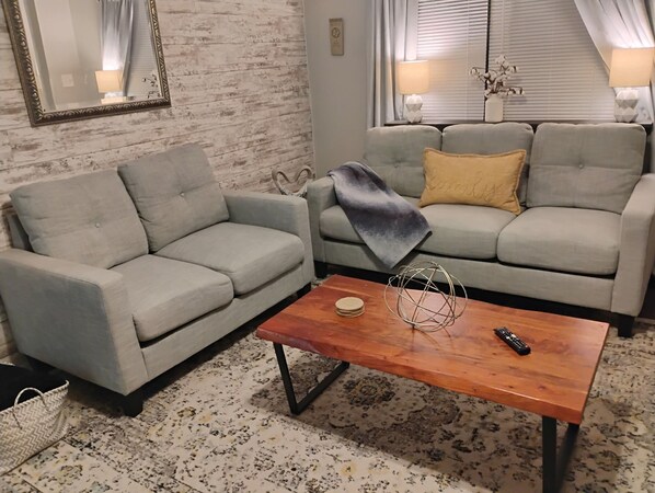 A living room with two grey sofas, a wooden coffee table, and a patterned rug.