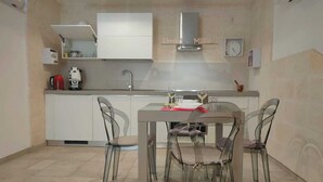 Eine moderne Küche mit Essbereich, ausgestattet mit Backofen, Mikrowelle, Kaffeemaschine und Spüle.
