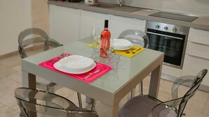 Eine moderne Küche mit Essbereich, inklusive Tisch für zwei Personen, Stühle, Herd und Mikrowelle.