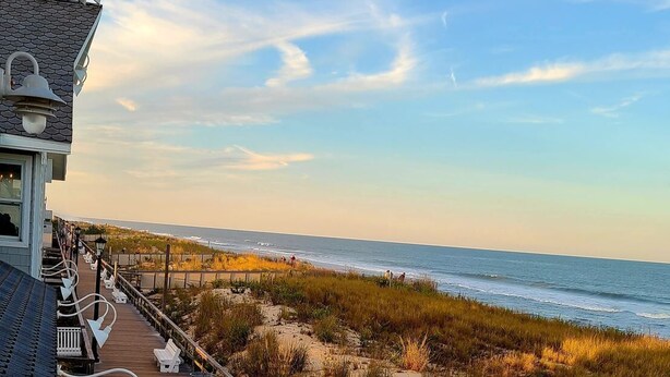 A wooden boardwalk leading to a beach with a view of the ocean.