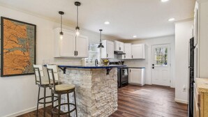 A modern kitchen with white cabinets, a stone island, and bar stools.