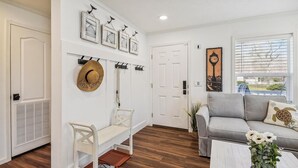 A living room with a grey sofa, a white bench, and a wall-mounted clock.