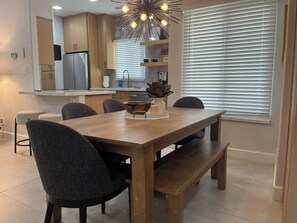 A modern kitchen with wooden cabinets, a built-in oven, and a dining area with a wooden table and chairs.
