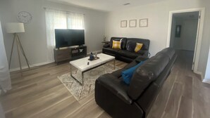 Ein Wohnzimmer mit einer Couch, einem Couchtisch, einem Fernseher und einer Lampe.