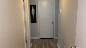 Ein Korridor mit Holzboden, einer weißen Tür und einer Deckenleuchte.