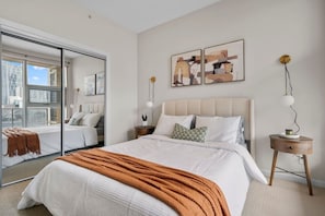 Quarto com cama grande, espelho e obras de arte na parede.