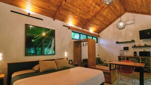 A bedroom with a large bed, a desk, a chair, a TV, and a painting on the wall.