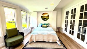 Un dormitorio con cama, una silla, una mesa redonda y un armario.