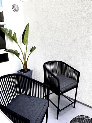 Relax in a tranquil outdoor space with two stylish chairs and a lush potted plant.