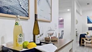 A kitchen counter with a bottle of Tangy Lemon, a wine bottle, and a fruit bowl containing lemons and limes. - Free Heated Pool Oasis: Coastal Bungalow Near Town & Beach (Bradenton)