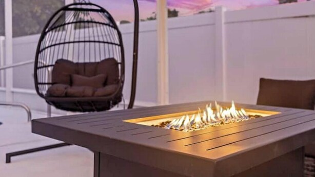 A modern outdoor seating area with a fire pit table and a hanging chair. - Free Heated Pool Oasis: Coastal Bungalow Near Town & Beach (Bradenton)