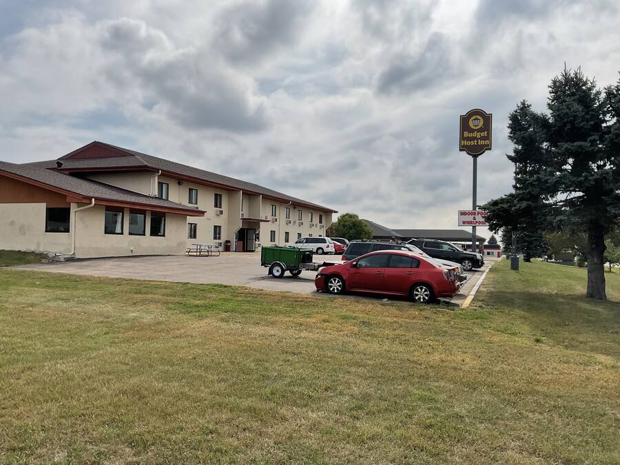 A motel with a parking lot, a green dumpster, and a sign for 'Budget Lost Inn'.
