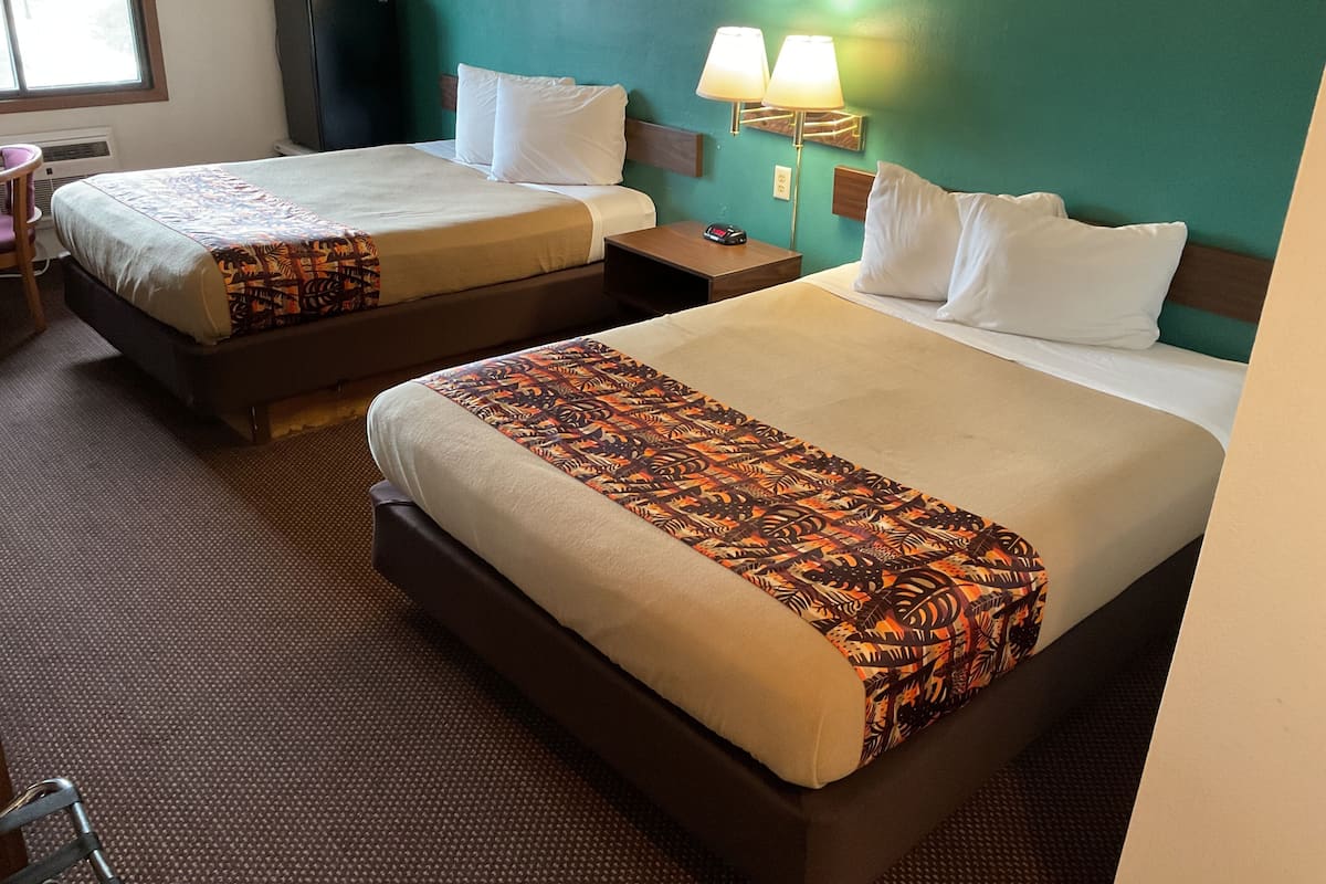 A hotel room with two beds, a TV, a desk, and a chair.
