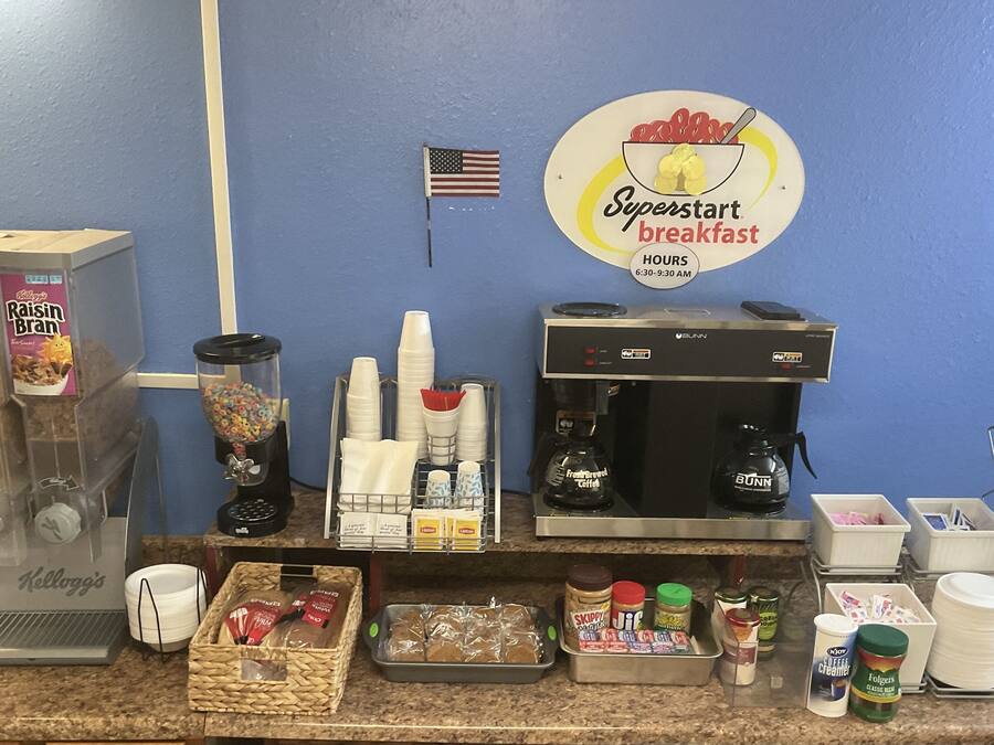 A breakfast station with a coffee machine, cereal dispensers, and condiments.