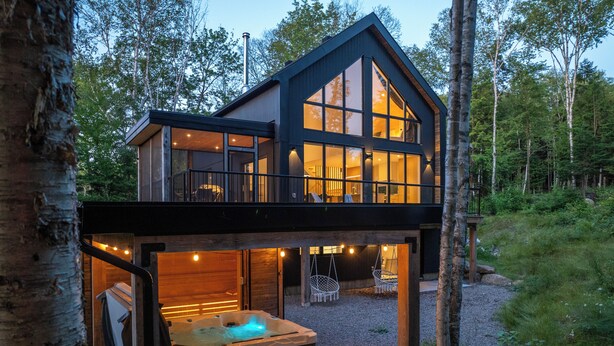 A modern two-story cabin with large windows, a hot tub, and a deck area. - Chalet Metsa Tremblant (Lac-Supérieur)