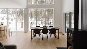 A spacious room with a large dining table, chairs, and a modern fireplace. - Chalet Metsa Tremblant (Lac-Supérieur)