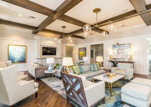 Cozy living room with a high ceiling, exposed beams, and a mix of traditional and modern furniture.