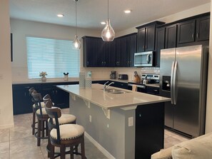 Enjoy cooking in this kitchen with a central island, bar stools, refrigerator, microwave, and gas stove.