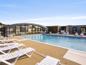 A swimming pool with lounge chairs and a covered seating area.