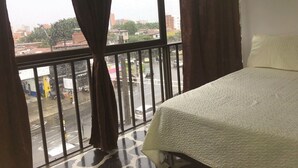 Une chambre d’hôtel avec un lit, une fenêtre avec des rideaux et une vue sur la rue.