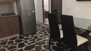 Une cuisine de taille réduite comprenant un réfrigérateur, une table à manger avec des chaises et un sol à motifs.