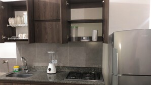 Une cuisine moderne avec des meubles de couleur bois foncé, un plan de travail en granit, un lave-vaisselle encastré, une cuisinière et un réfrigérateur.