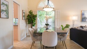 A dining area with a round table, chairs, a chandelier, and a view of the outdoors. - Hidden Gem in Rancho Mirage (Rancho Mirage)
