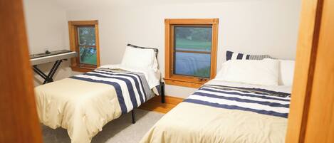 A bedroom with two beds, a window, and a desk.